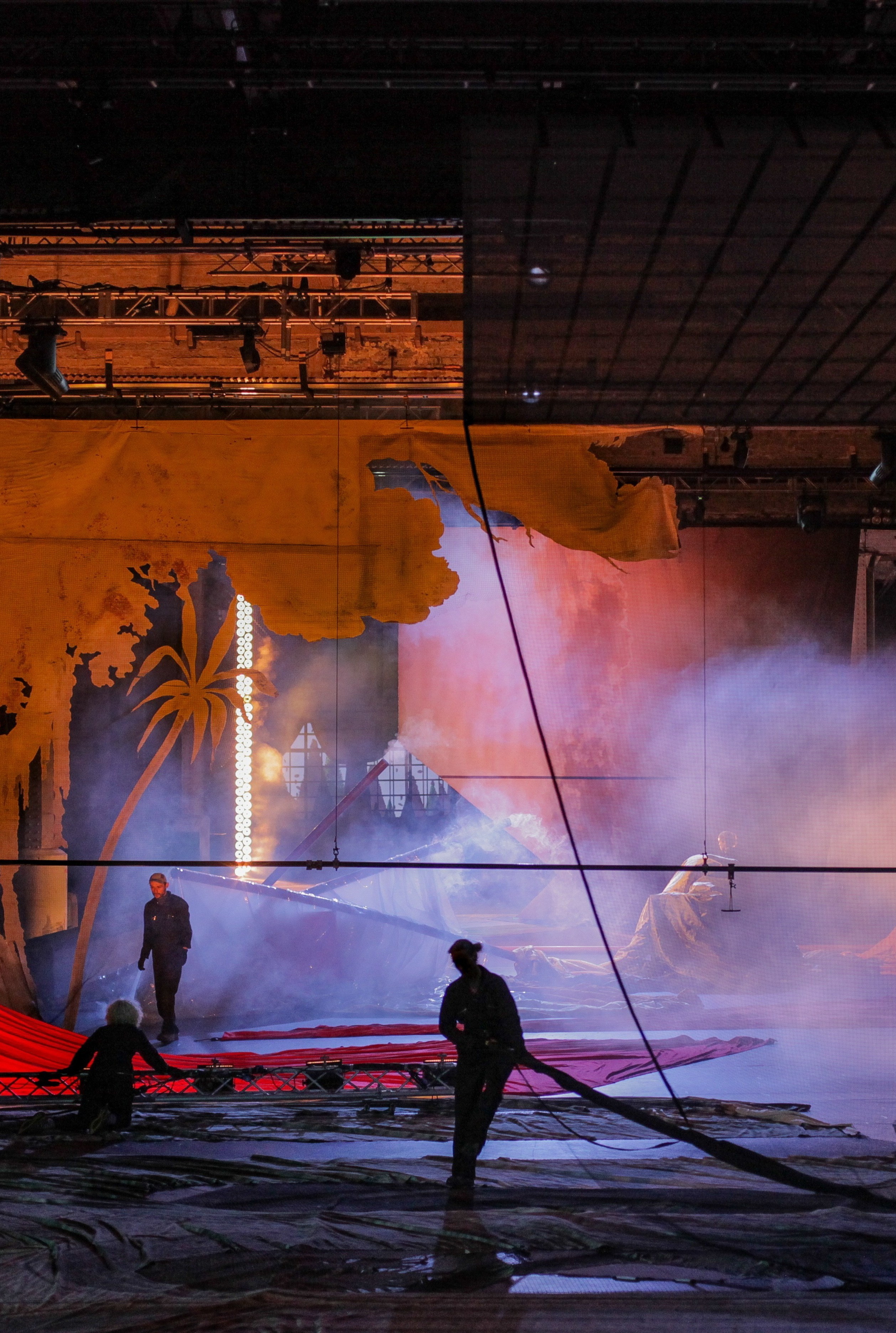 Performers on stage during Everything That Happened and Would Happen by Heiner Goebbels, with smoke, set and large fabric elements.