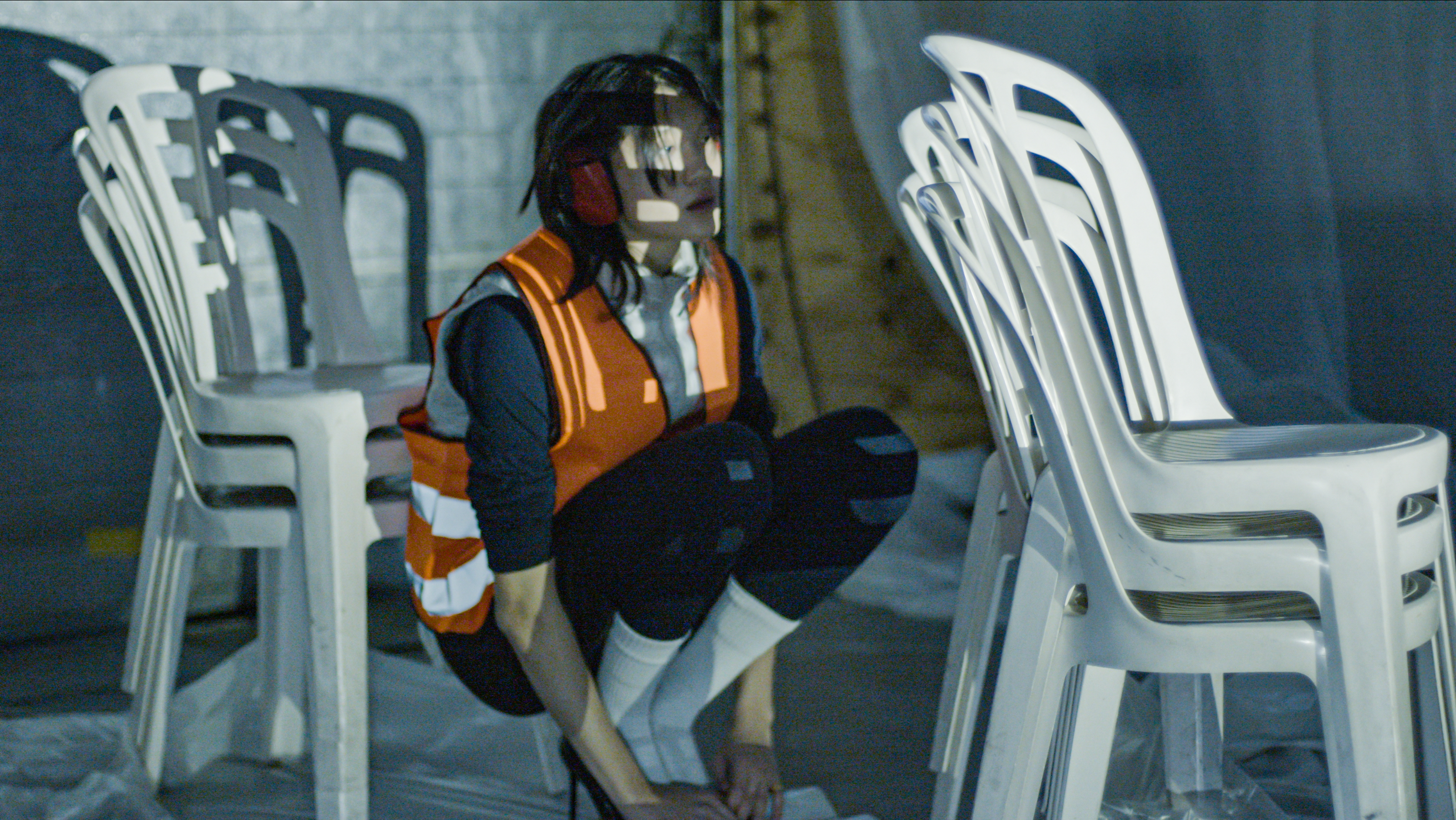 Performer observing space among plastic chairs during Slab Altar residency GRASpunt Amsterdam